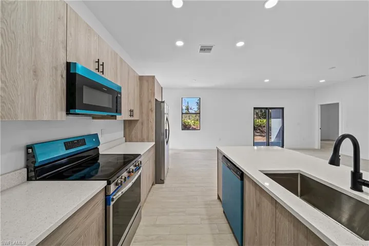 Kitchen with stainless steel appliances, light stone countertops, modern cabinets, and recessed lighting