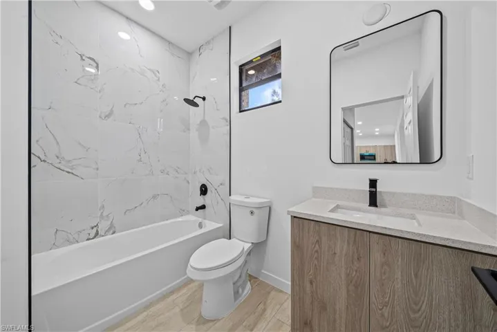 Bathroom with vanity, shower / bath combination, and light wood finished floors
