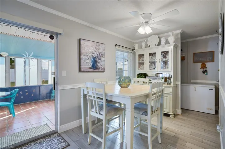 Dining area with light wood-finish flooring, a ceiling fan with integrated lighting, and chair rail molding