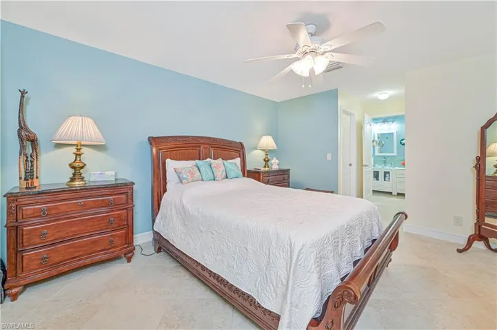 Primary bedroom with ensuite bath, ceiling fan, a closet, and light tile patterned floors