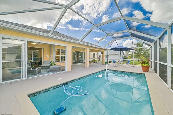 View of pool featuring outdoor lounge area, glass enclosure, ceiling fan, and a patio area