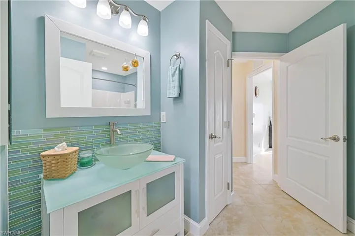 Guest bathroom featuring tile patterned flooring, vanity, a shower, and backsplash