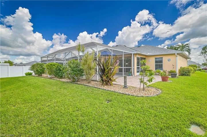 Rear view of property featuring a yard, screen enclosure, and a patio area