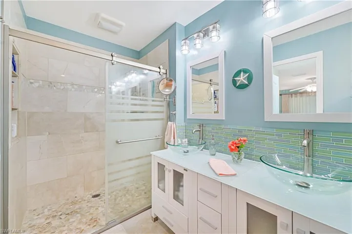 Primary bathroom featuring tile patterned floors, decorative backsplash, vanity, and walk in shower