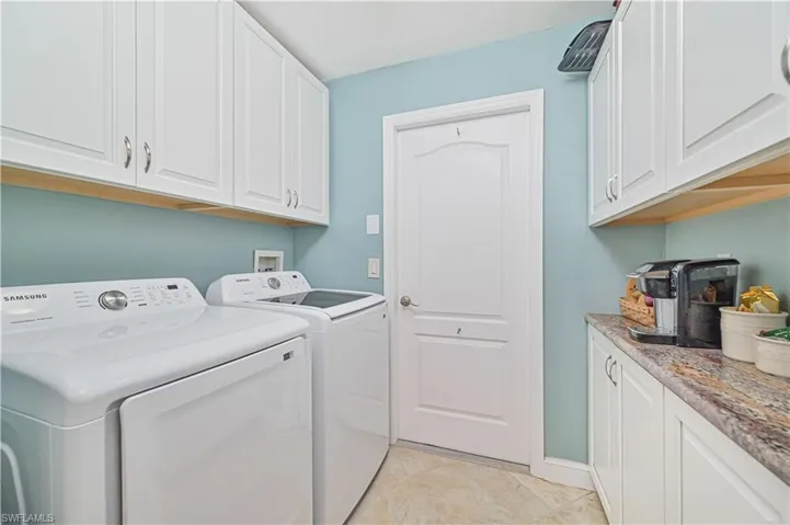 Laundry area featuring light tile patterned flooring, cabinets, and separate washer and dryer