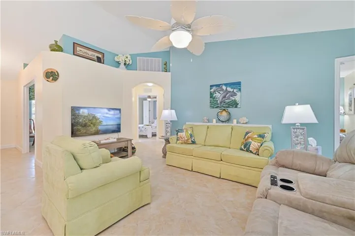 Tiled living room with ceiling fan and lofted ceiling