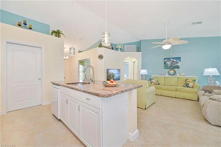 Kitchen with pendant lighting, a center island with sink, high vaulted ceiling, and white cabinetry