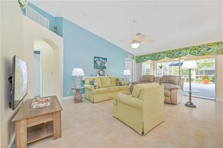 Tiled living room with ceiling fan and high vaulted ceiling