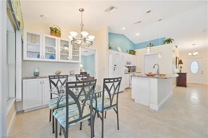 Dining area featuring light tile patterned floors, sink, lofted ceiling, and a notable chandelier