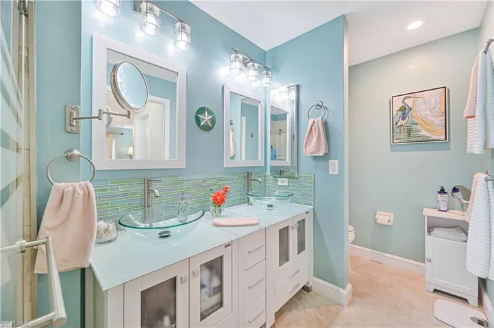 Primary bathroom with tile patterned flooring, vanity, toilet, and tasteful backsplash