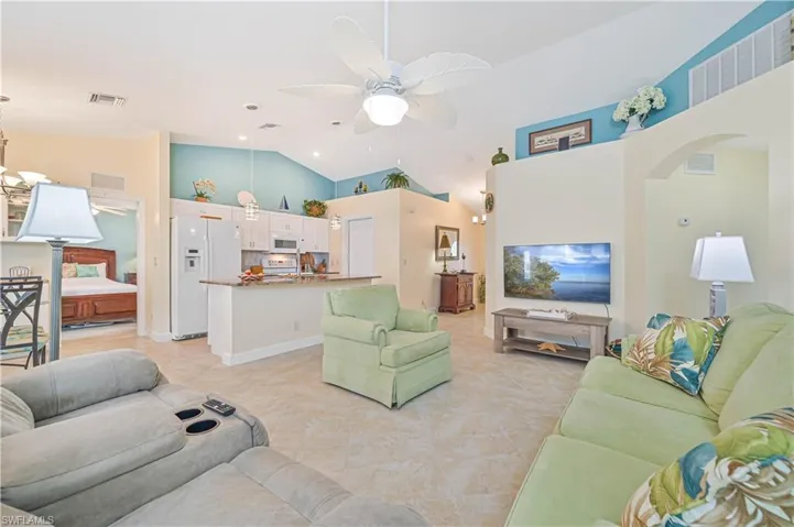 Living room featuring light tile patterned floors, high vaulted ceiling, and ceiling fan