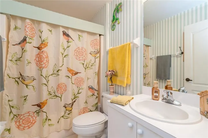 Bathroom featuring curtained shower, vanity, and toilet