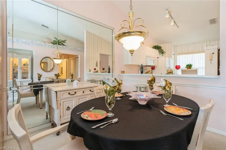 Carpeted dining space with rail lighting and vaulted ceiling