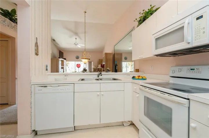 Kitchen with white appliances, ceiling fan, sink, decorative light fixtures, and white cabinetry