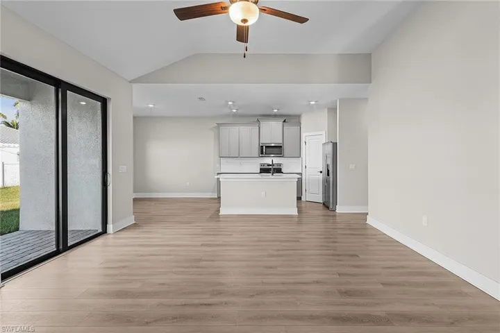 Unfurnished living room with wood finish floors, lofted ceiling, ceiling fan, and recessed lighting