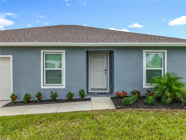 View of front of house with stucco siding, a shingled roof, a front lawn, and a garage