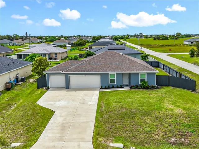 Ranch-style house featuring roof with shingles, an attached garage, concrete driveway, solar panels, and a residential view