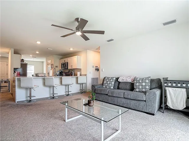 Living area with light carpet and ceiling fan