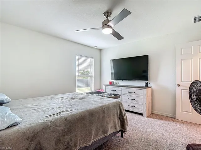 Bedroom featuring light colored carpet, a textured ceiling, and ceiling fan