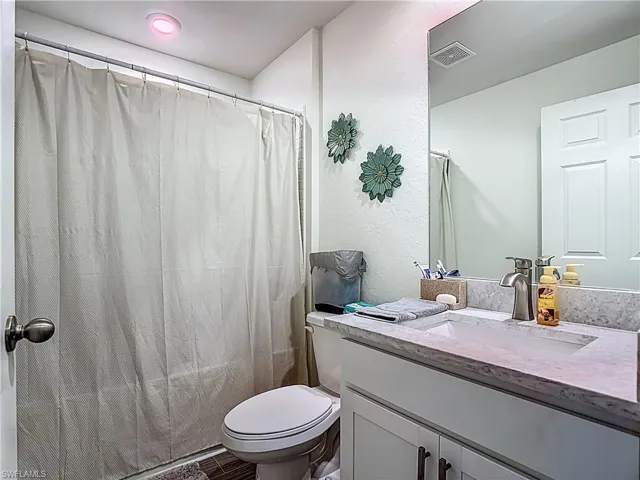 Full bathroom with vanity, a textured wall, and shower / bathtub combination with curtain