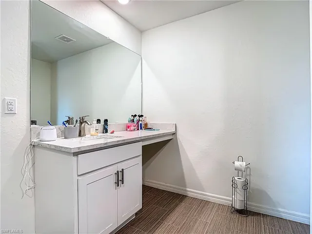 Bathroom with a textured wall and vanity