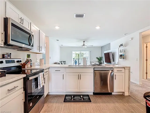 Kitchen with stainless steel appliances, white cabinets, a peninsula, recessed lighting, and open floor plan