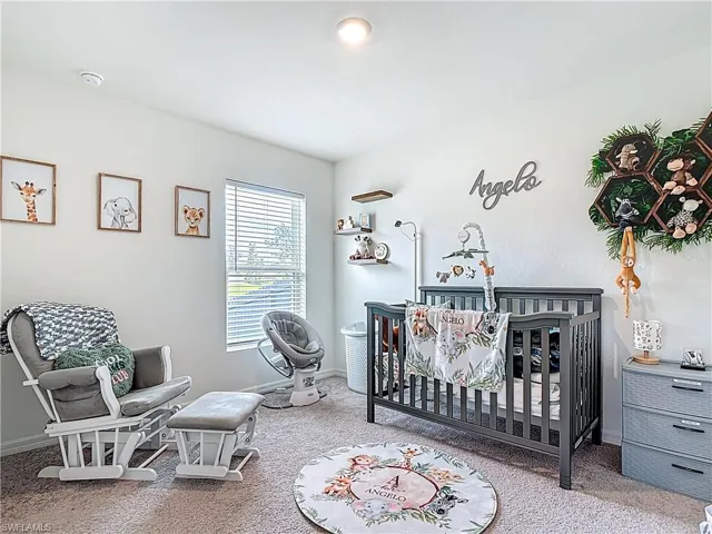 Carpeted bedroom with a crib and baseboards