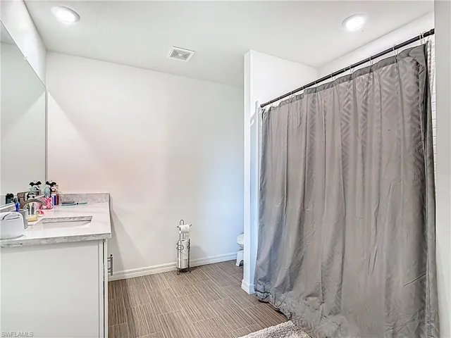 Full bath with vanity, a shower with shower curtain, recessed lighting, and wood finish floors