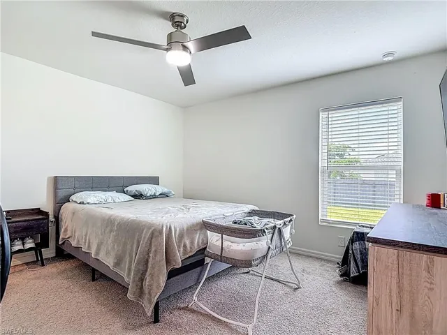 Bedroom with light carpet, a ceiling fan, and a textured ceiling