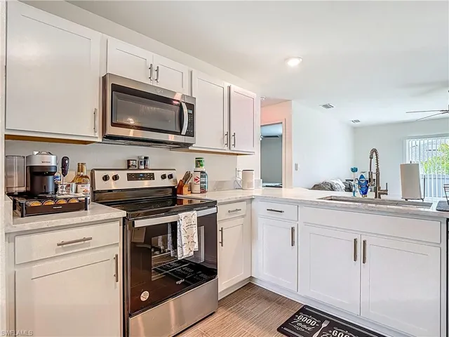Kitchen featuring appliances with stainless steel finishes, white cabinetry, light stone countertops, ceiling fan, and recessed lighting