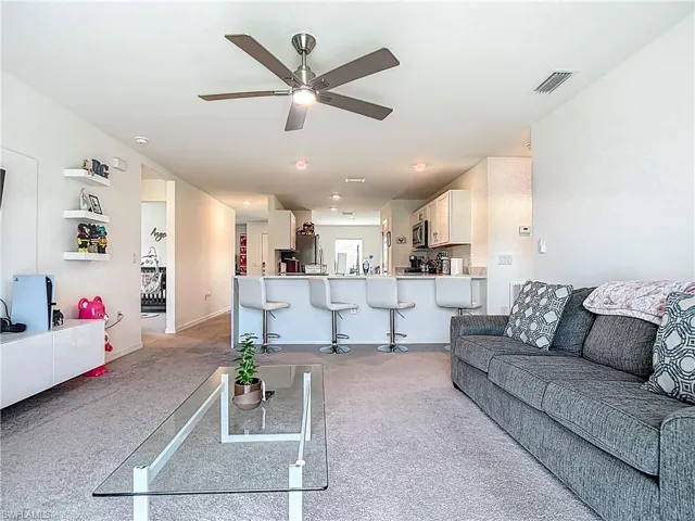 Living room with light colored carpet and ceiling fan