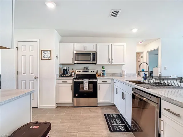 Kitchen featuring stainless steel appliances, white cabinets, light stone countertops, recessed lighting, and wood tiled floors