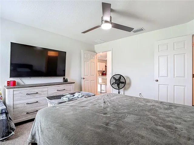 Bedroom with a ceiling fan, a textured ceiling, and carpet flooring