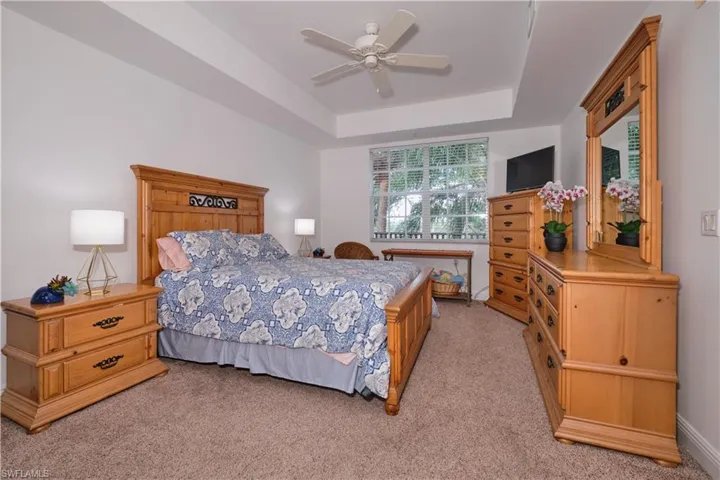 Carpeted bedroom featuring a tray ceiling and ceiling fan