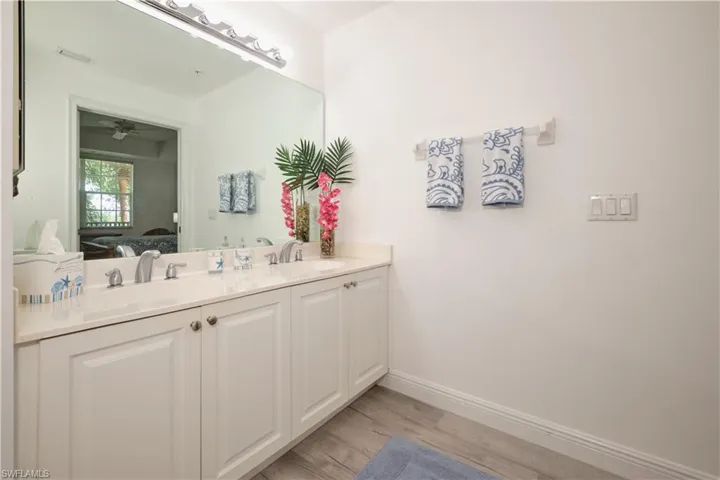 Bathroom with wood-type flooring, double sink vanity, and ceiling fan