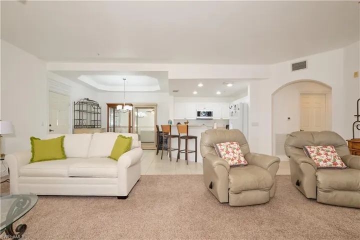 Tiled living room featuring a raised ceiling and an inviting chandelier