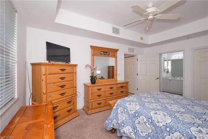 Carpeted bedroom featuring connected bathroom and ceiling fan