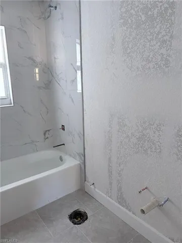 Bathroom featuring a textured wall and shower / bath combination