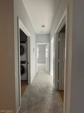 Hall featuring carpet and stacked washing machine and dryer