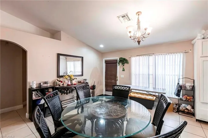 Dining area featuring light tile patterned floors, lofted ceiling, arched walkways, and recessed lighting