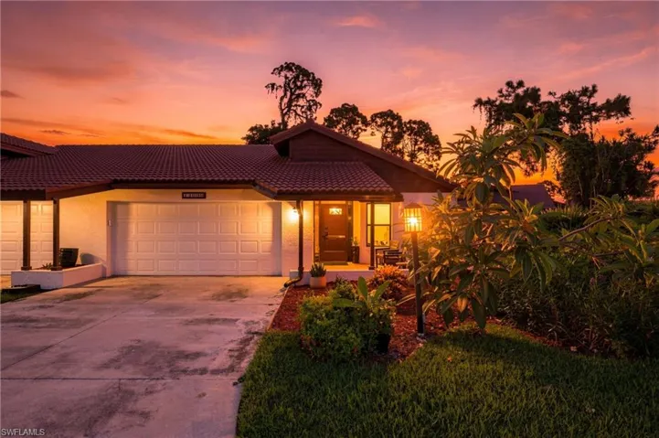 Terracotta tile roofing, stucco exterior, two-car garage, established landscaping, and a covered entryway