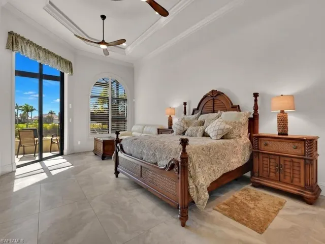 Expansive room featuring large format tile flooring, a tray ceiling with crown molding, and two ceiling fans
