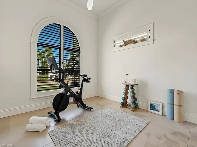Room featuring a large arched window with horizontal blinds, complemented by a rectangular window with white plantation shutters