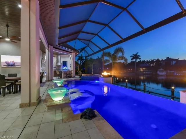 Screened pool deck featuring a dark-bottom pool with integrated spa and water features