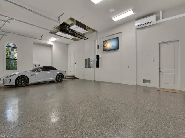 Spacious garage featuring a durable epoxy floor, arched window, and integrated overhead lighting