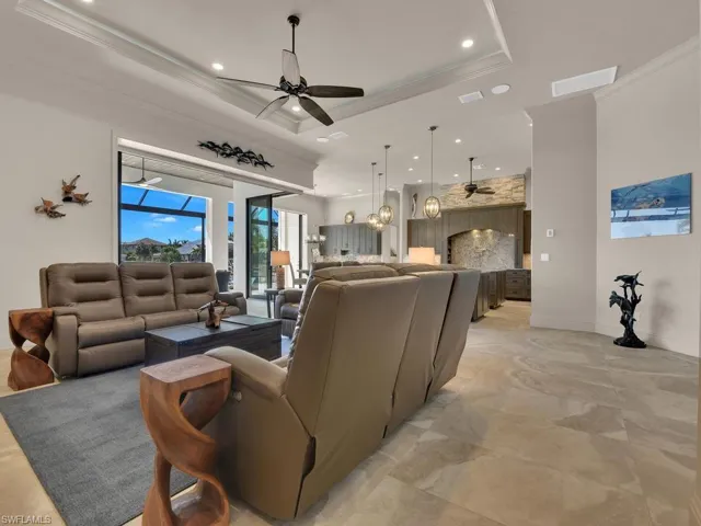 Open-concept living area with large format tile flooring and tray ceiling