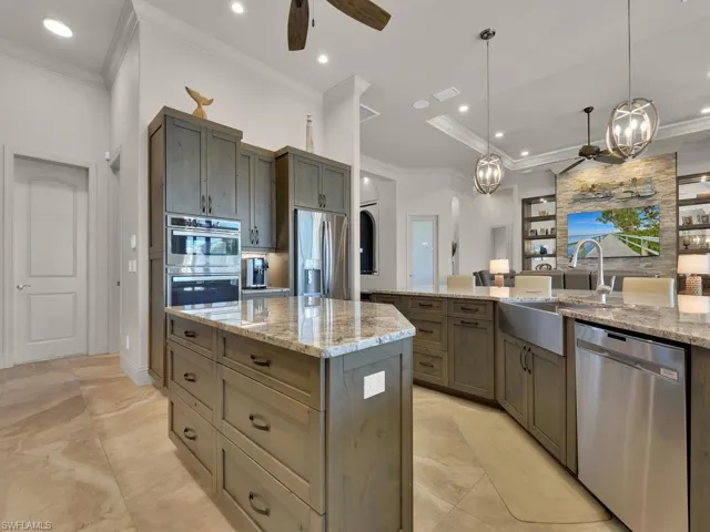 Gourmet kitchen featuring a large central island, light-toned cabinetry, stainless steel appliances, and stone countertops