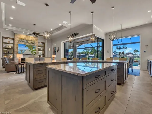 Spacious kitchen featuring two large islands with stone countertops, integrated cabinetry, and pendant lighting