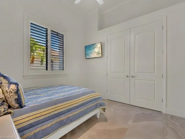 Window featuring louvered shutters, double closet doors, and light-toned flooring