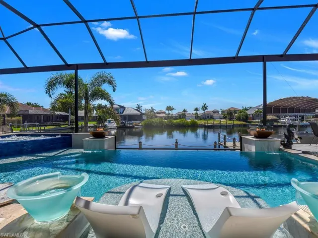 Screened outdoor living area with an infinity-edge pool, integrated spa, and waterway frontage